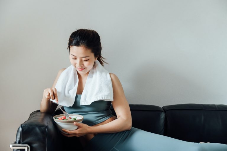 Young Asian woman eating salad after exercise